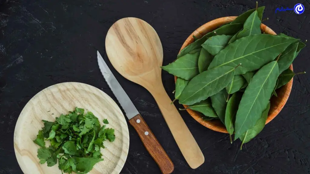 دو بشقاب برگ سنای تازه با یک قاشق چوبی ویک چاقو با دسته چوبی